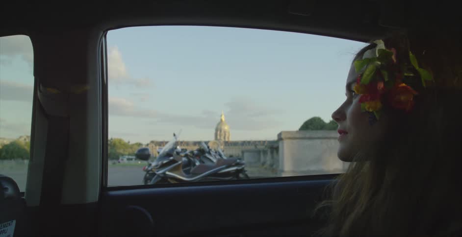 A woman is sitting in a car looking out the window as it drives