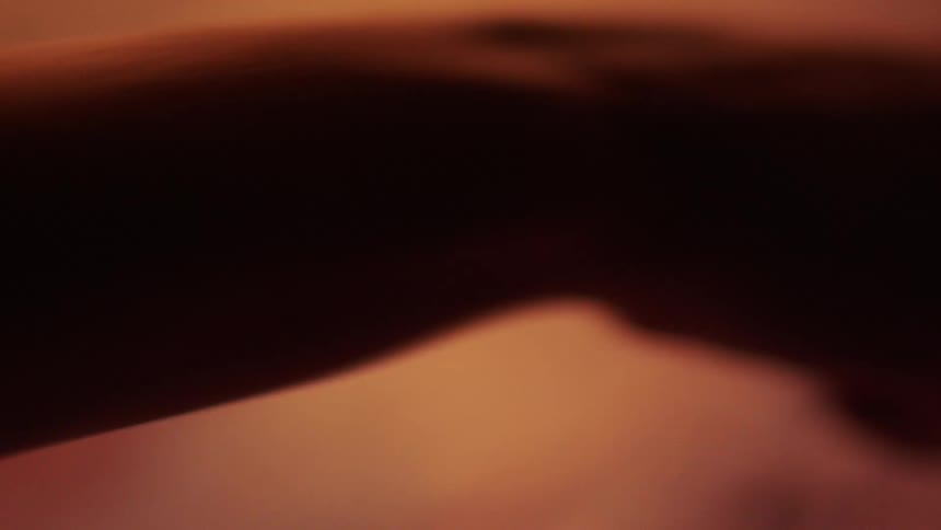An artist using a painting knife scratches across the surface of a canvas in a frantic manner