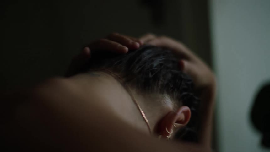 A woman is leaning forward in the dark room