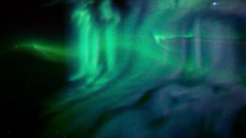 Green and blue lights shimmer and glow against black