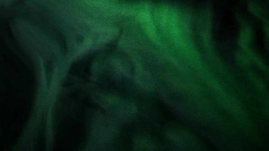 Green light glows and shimmers against black