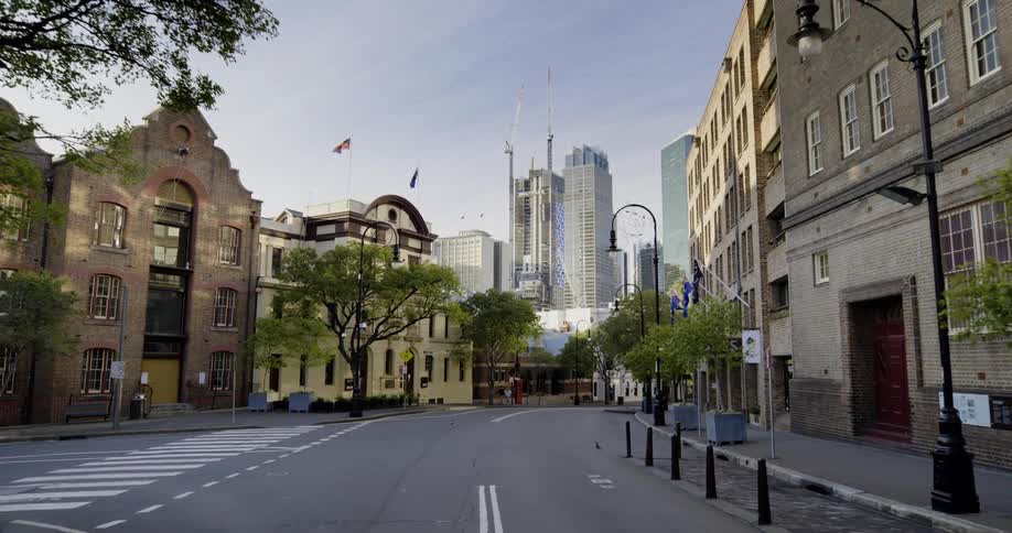 A city street is lined with a number of brick buildings and several towering skyscrapers loom in the background