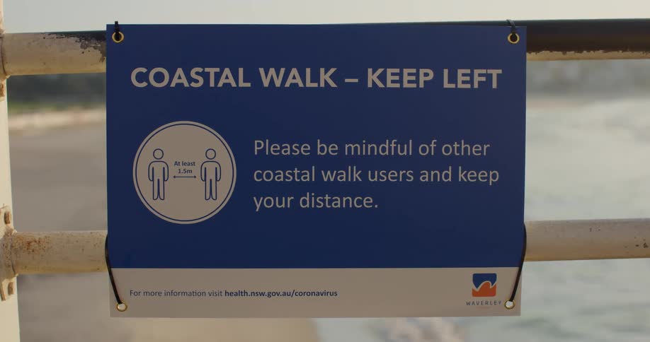 A sign hanging on a bannister on the coast