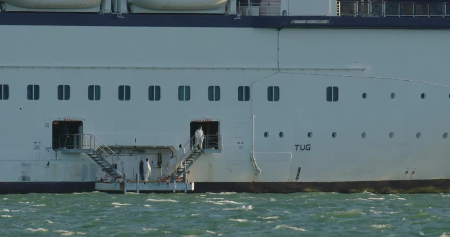 The uniformed staff on a ship descend an external staircase to gather on a small platform on the outside of the ship