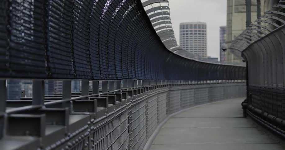 An empty pedestrian bridge walkway with city buildings behind