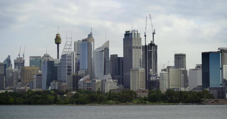 A coastal city with trees and buildings and skyscrapers with the sky and clouds in the background
