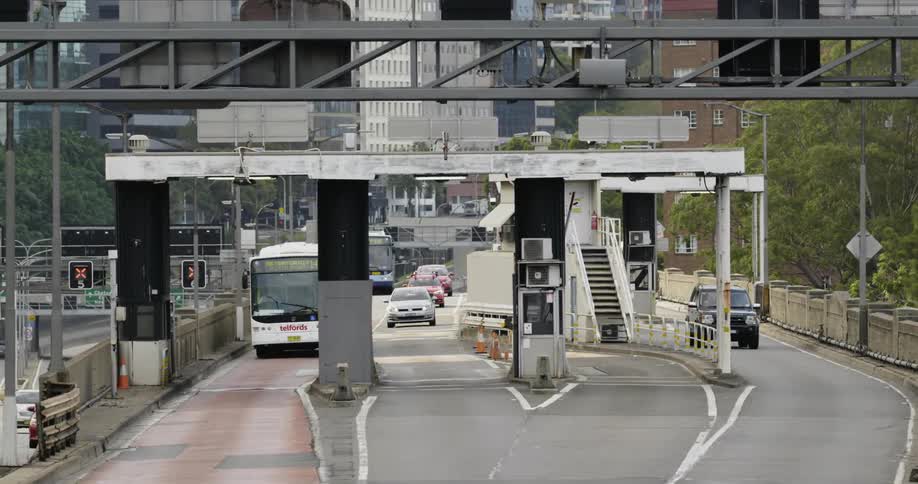 Buses and cars approach toll booths at a highway merge
