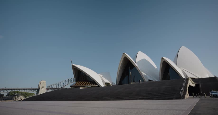 An opera house with a bridge buildings trees and the sky in the background
