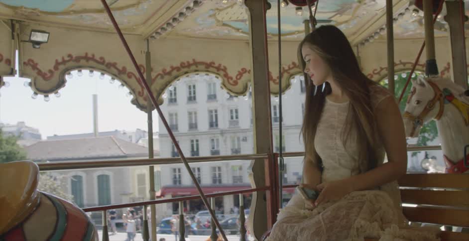 A woman in an ivory dress rides a carousel