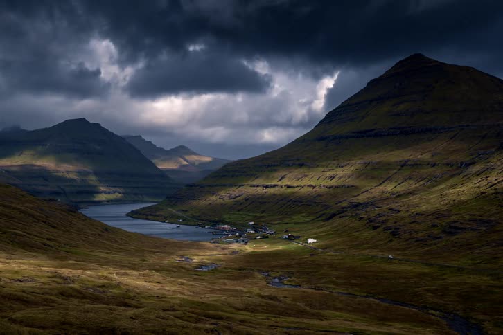A river in a valley between hills with the sky and clouds in the background