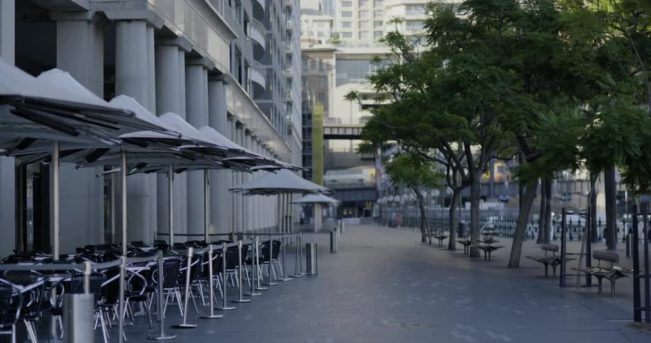 A city with chairs tables and umbrellas with a train in the background