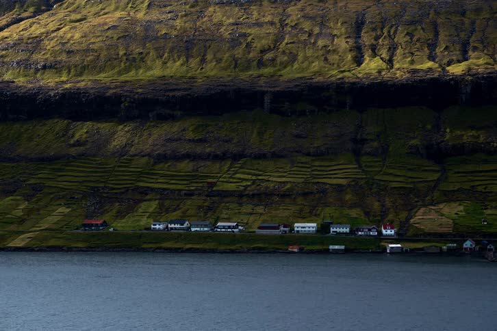 A small town with houses close to the coast with a cliff in the background