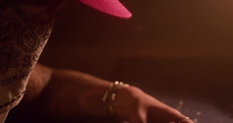 Woman wearing hat and bandana across face works on metal