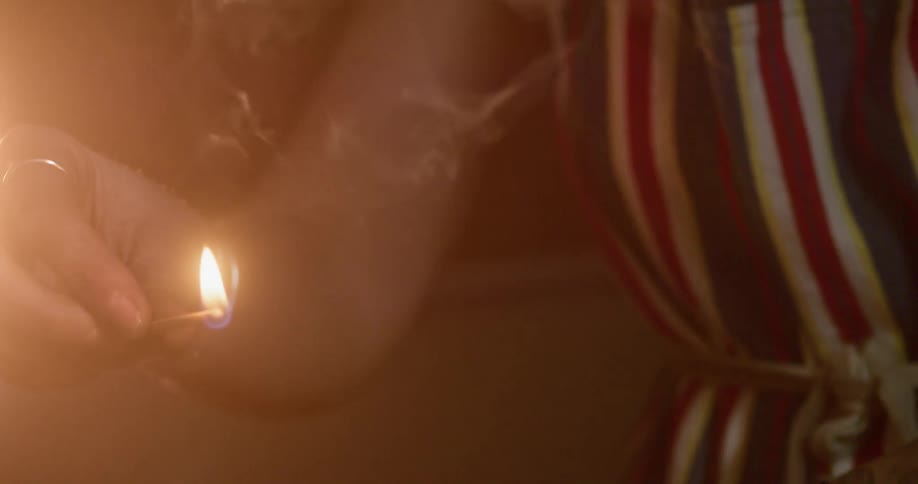 A person striking a match on a matchbox then lighting a torch with fire