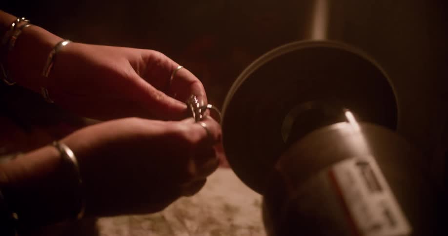 Person polishes ornate ring against rotating disk of machine