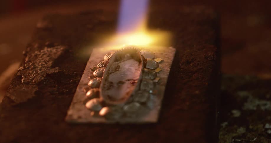A person with a blowtorch putting flames on a piece of metal