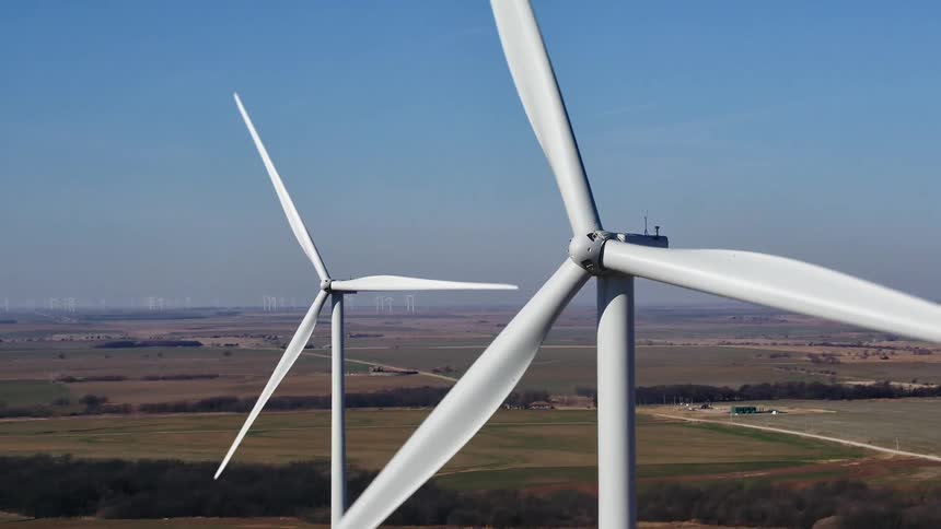 Wind turbines standing out against the blue sky spin around in the wind farm