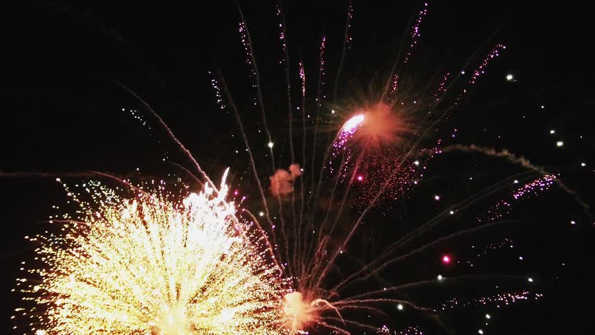 Fireworks exploding in a night sky with colors lights and smoke