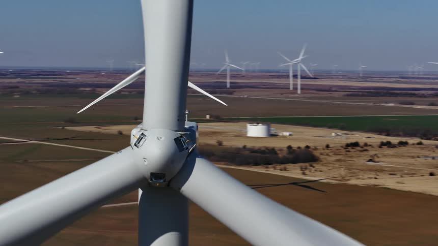 Close up of a wind turbine spinning around in a wind farm on sunny day