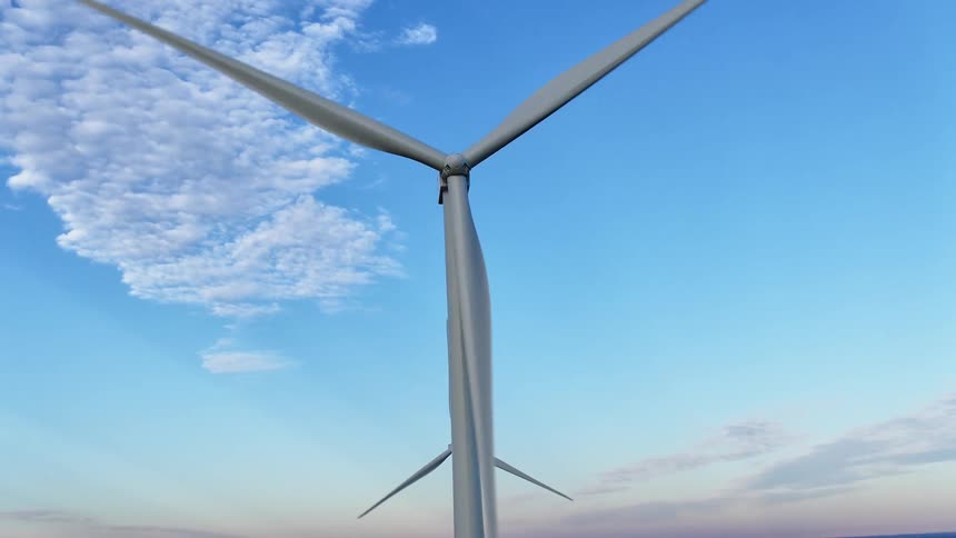 Wind turbines rotating in a wind turbine farm with the sky and clouds in the background