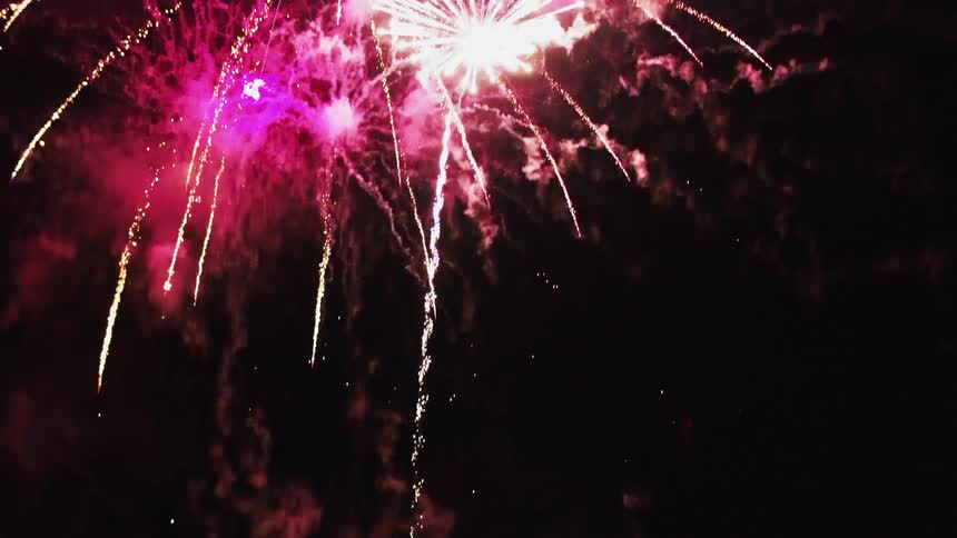 Fireworks explode in a dark night sky