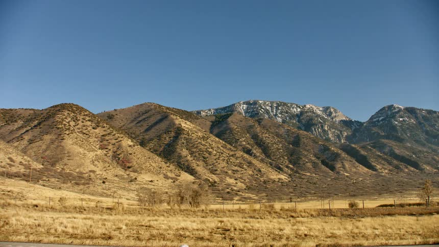 Vehicles driving down a street in front of a mountain range
