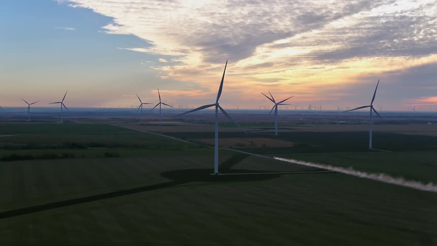 Wind turbines on a wind turbine farm on a grassy plain with the sky and clouds in the background
