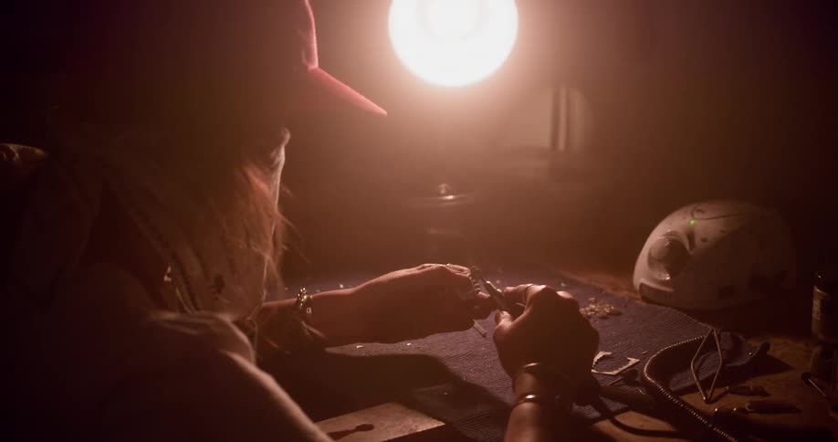 A person sits in a dark room using tools
