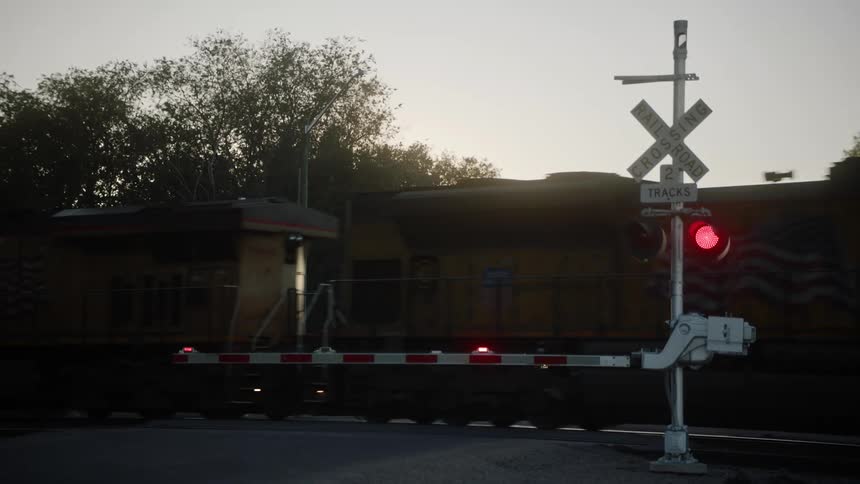 A cargo train moving on a train track with shipping containers with trees and the sky in the background