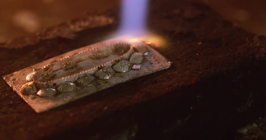 A piece of metal is torched with a flame
