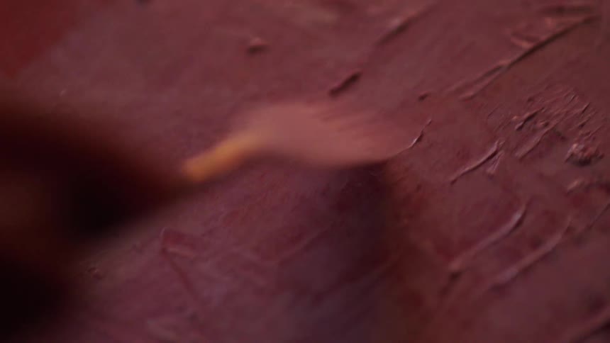 A persons hand holding a paintbrush applying paint