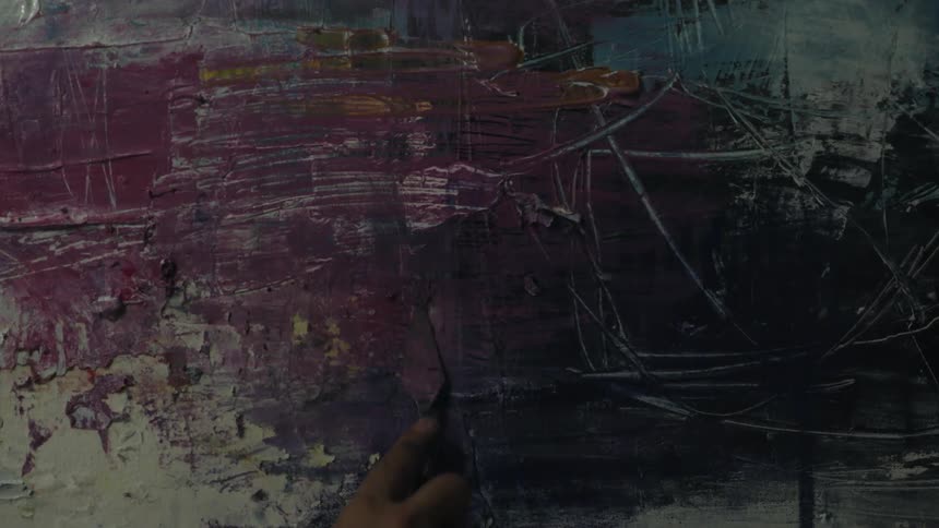 A person scrapes lines into a painting