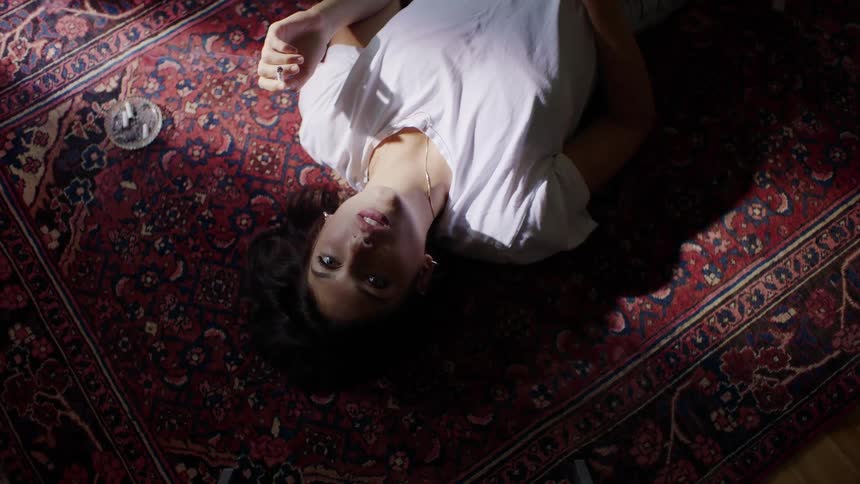 A young woman lying on the floor smoking