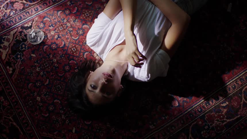 A woman is laying on the carpet in the dark room