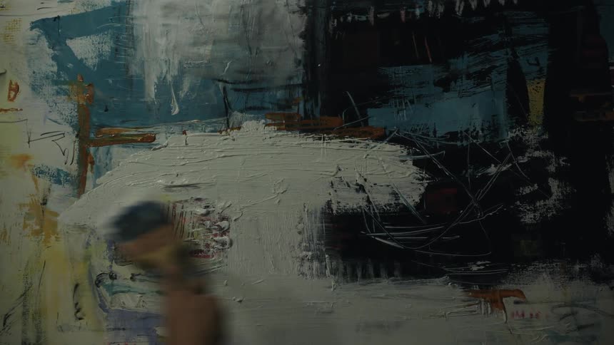 A person is putting white paint on the canvas