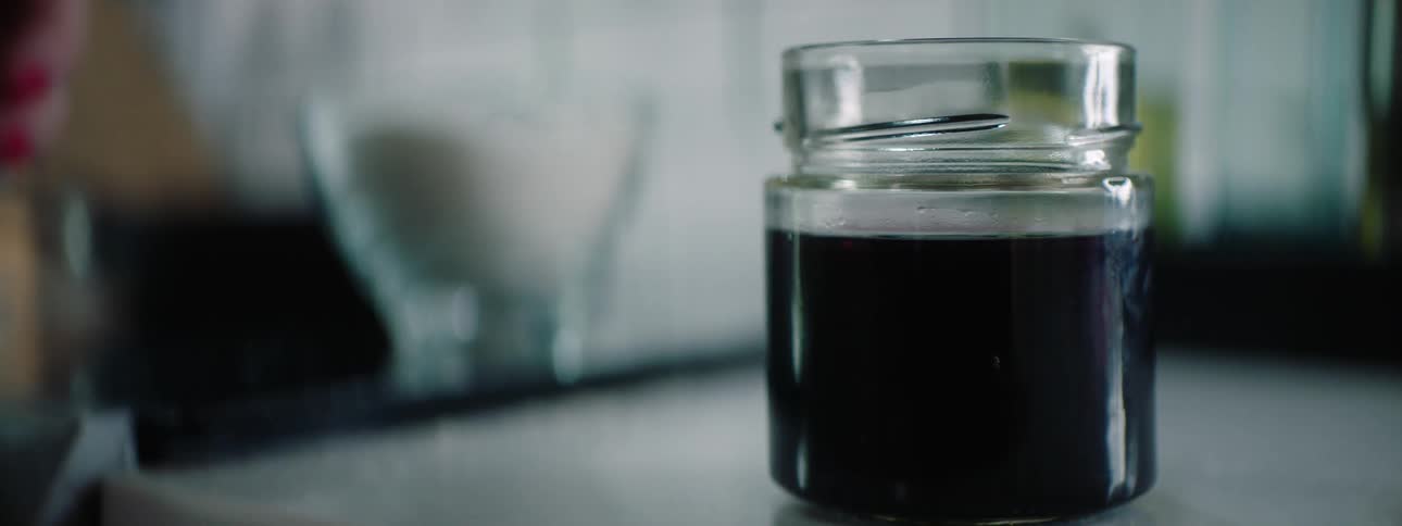 Woman with red fingernail polish adds lid to jar and tightens it