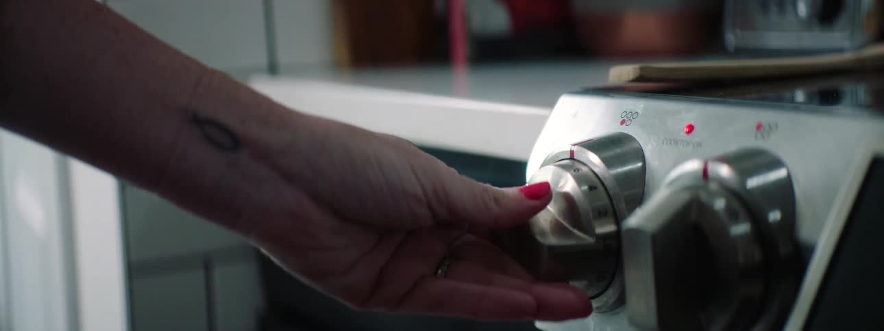Womans hand turns control knob in the kitchen
