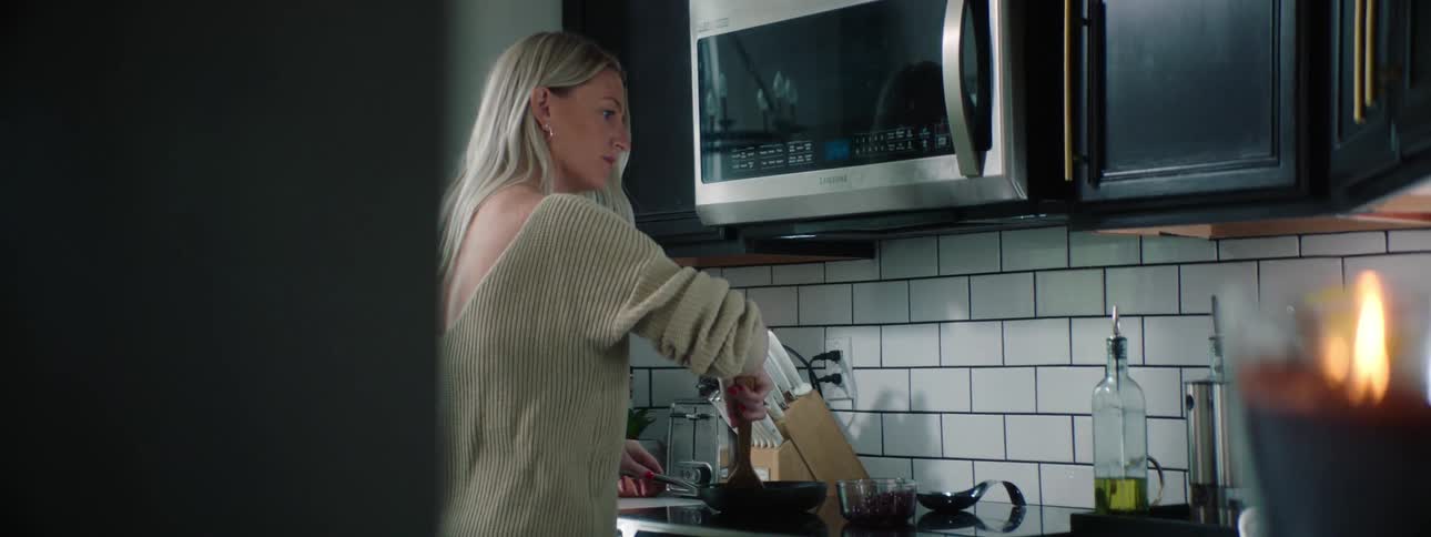 A woman uses a wooden spatula to press food in a skillet atop an oven in a kitchen during the day