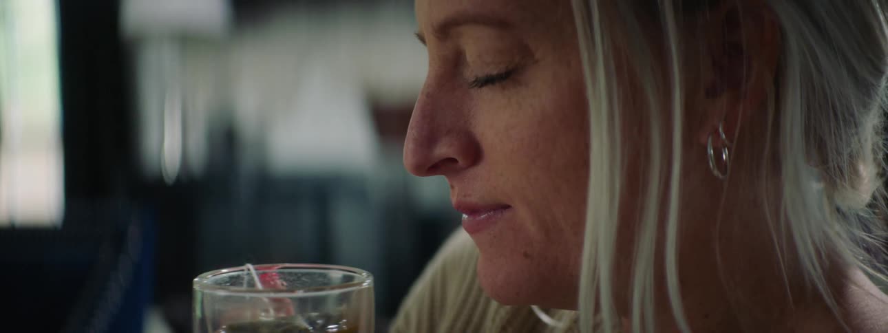 Blonde woman sniffs cup still containing tea bag