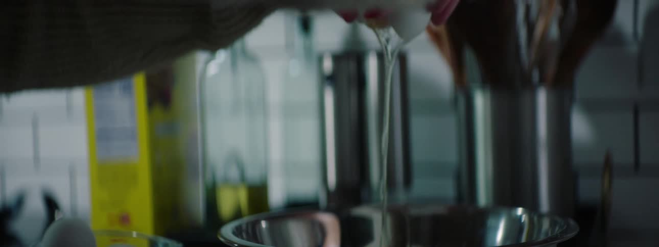 A woman at home cracks an egg in to a bowl