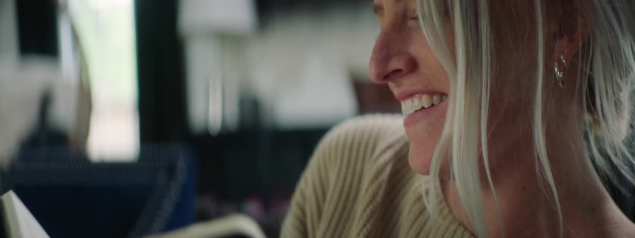 A young woman smiles and laughs as she finishes writing something in her notebook and puts it away