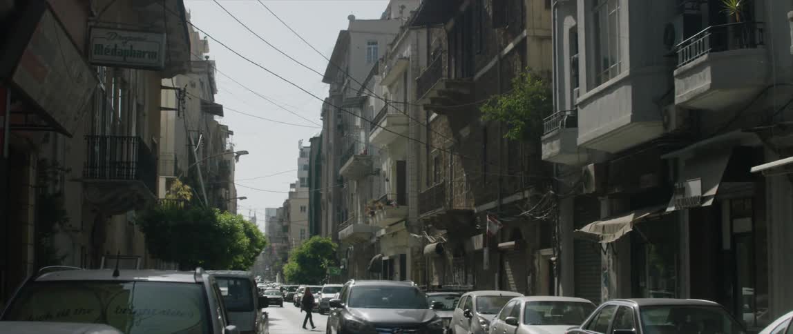 Vehicles are driving down a busy street