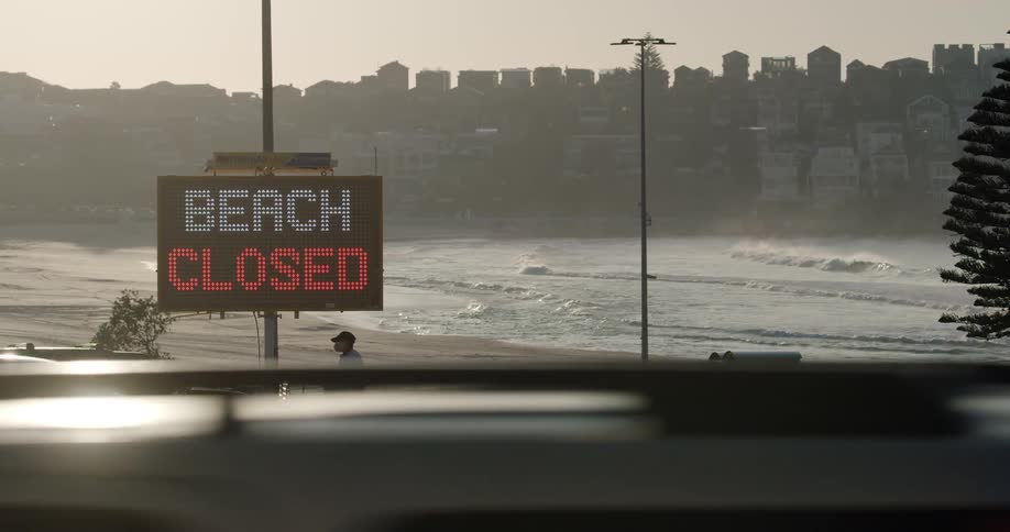 An electric sign displays a message that the beach near a large downtown area is closed