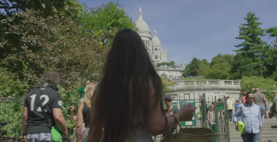 A long haired woman walks toward a gate