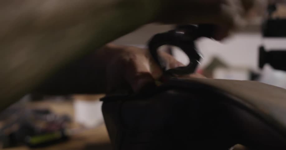 A man is repairing a shoe with a tool