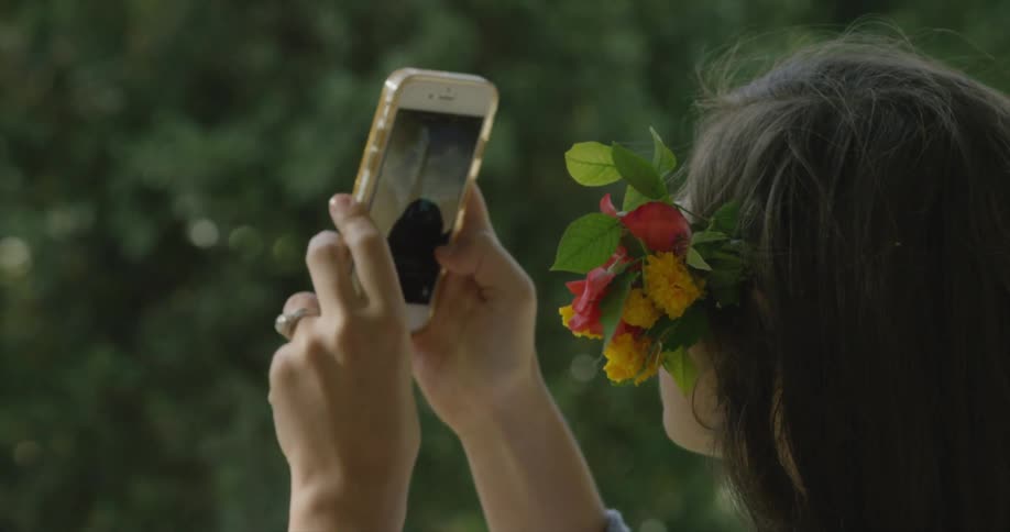 A woman is using a phone to photograph on a sunny day
