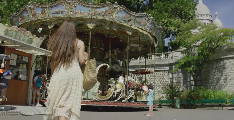 A woman holding a bag is walking over to a carousel