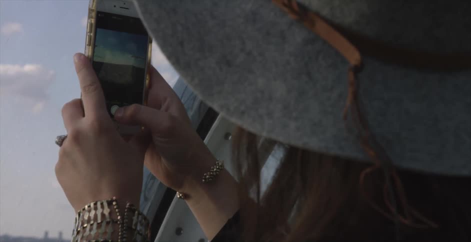 A woman points her phone out a window to take a photo