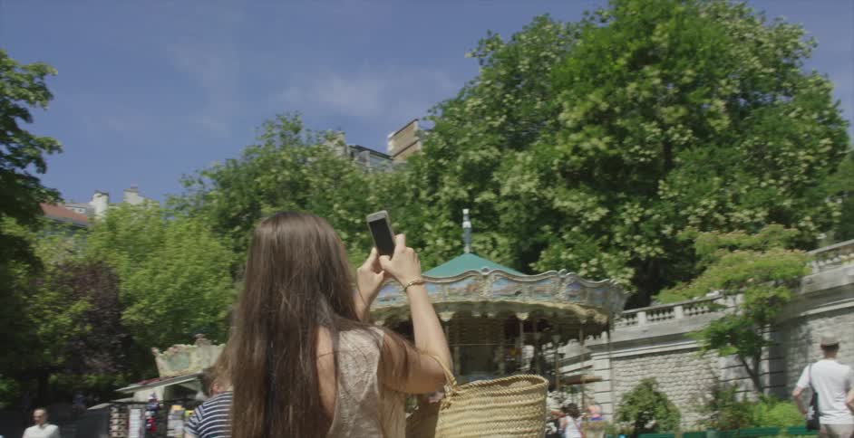 A woman is taking some photos of a building with her phone