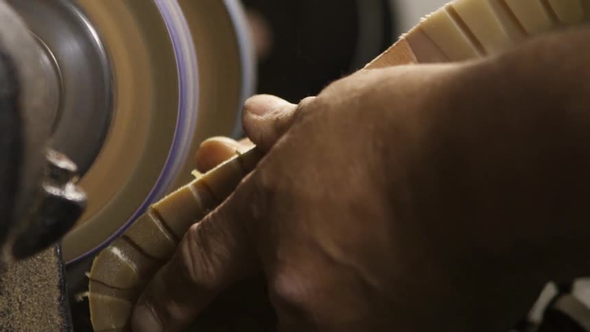 A man sands down leather tags on a shoe